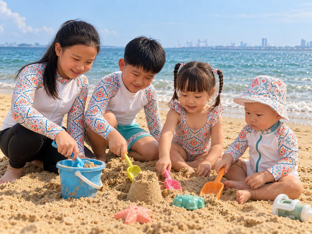 Four children wearing KaiLynn Coral Bloom swimwear build sandcastles at the beach.